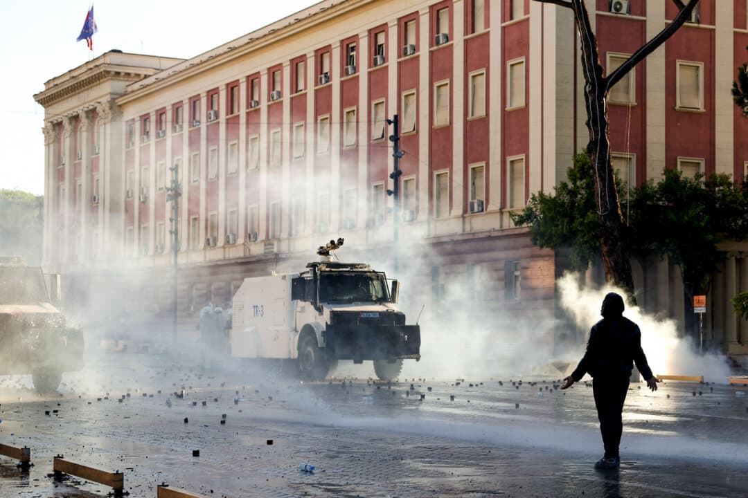 A protester faces riot police water-cannon vehicles as tear gas billows during an anti-government demonstration in central Tirana, Albania, on Oct. 16, 2026. Protests continued for a fourth consecutive day over university conditions and demands for Prime Minister Edi Rama's resignation. (Adnan Beci/AFP via Getty Images)