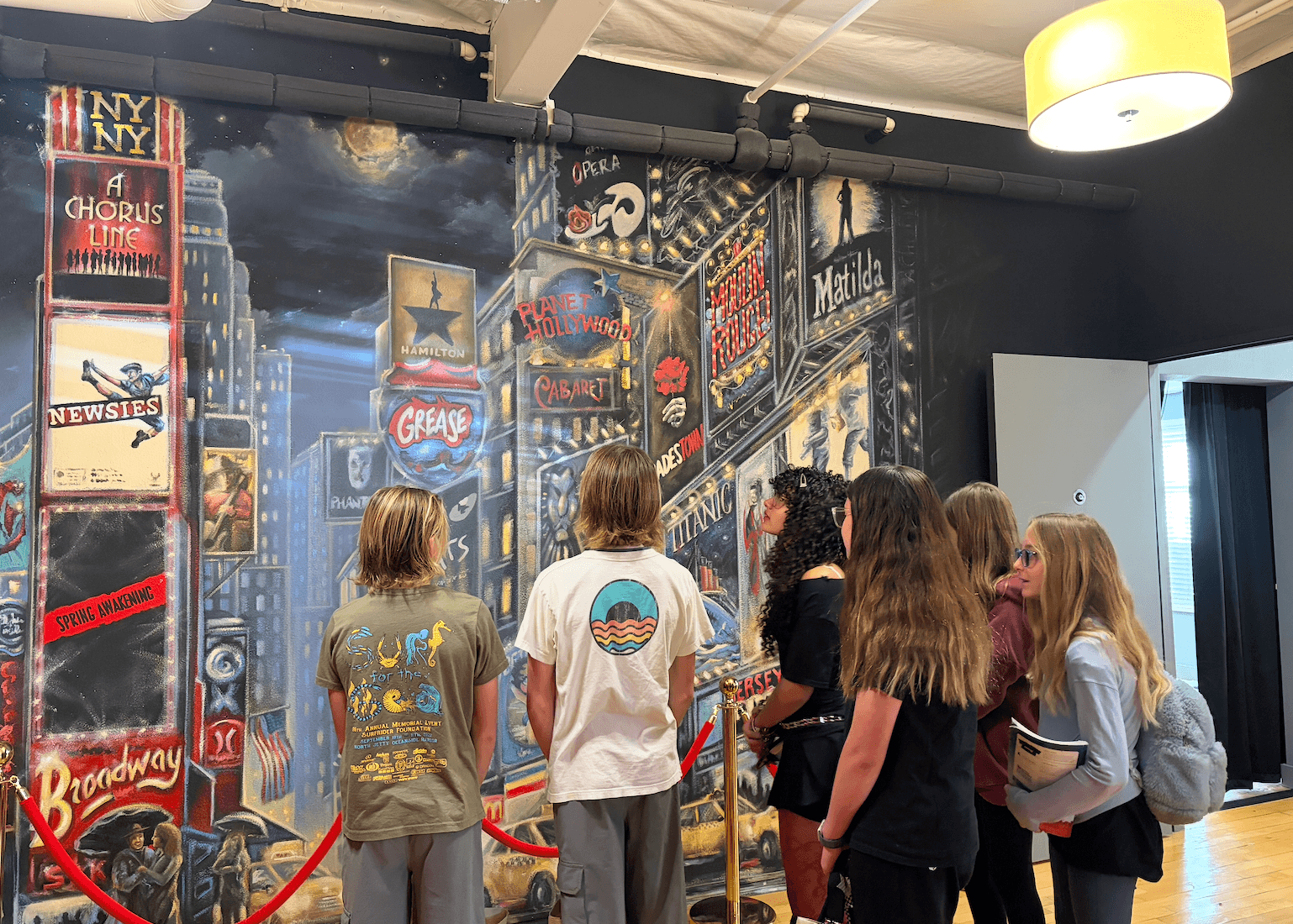 A group of students looks at a mural honoring famous musicals. (Courtesy of Bravo Players Foundation)