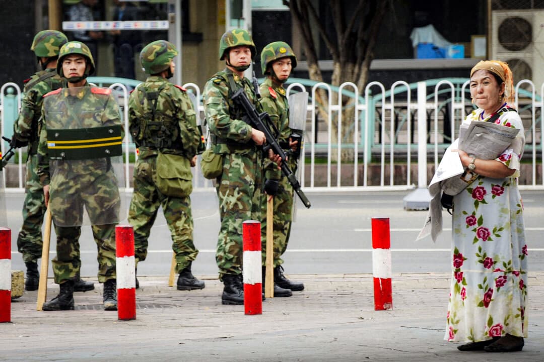 Chinese paramilitary policemen keep watch as an ethnic Uyghur woman (R) sells newspapers in the Uyghur district of the city of Urumqi in China's Xinjiang region on July 14, 2009. (Peter Parks/AFP via Getty Images)